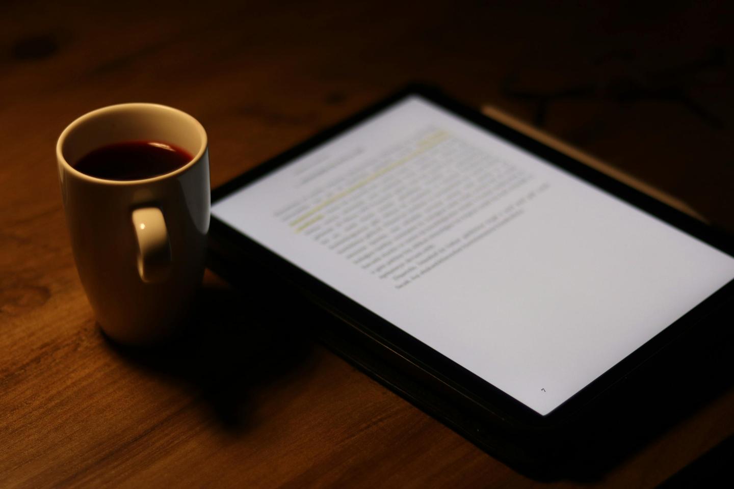 Lecture numérique sur tablette accompagnée d'une tasse de café